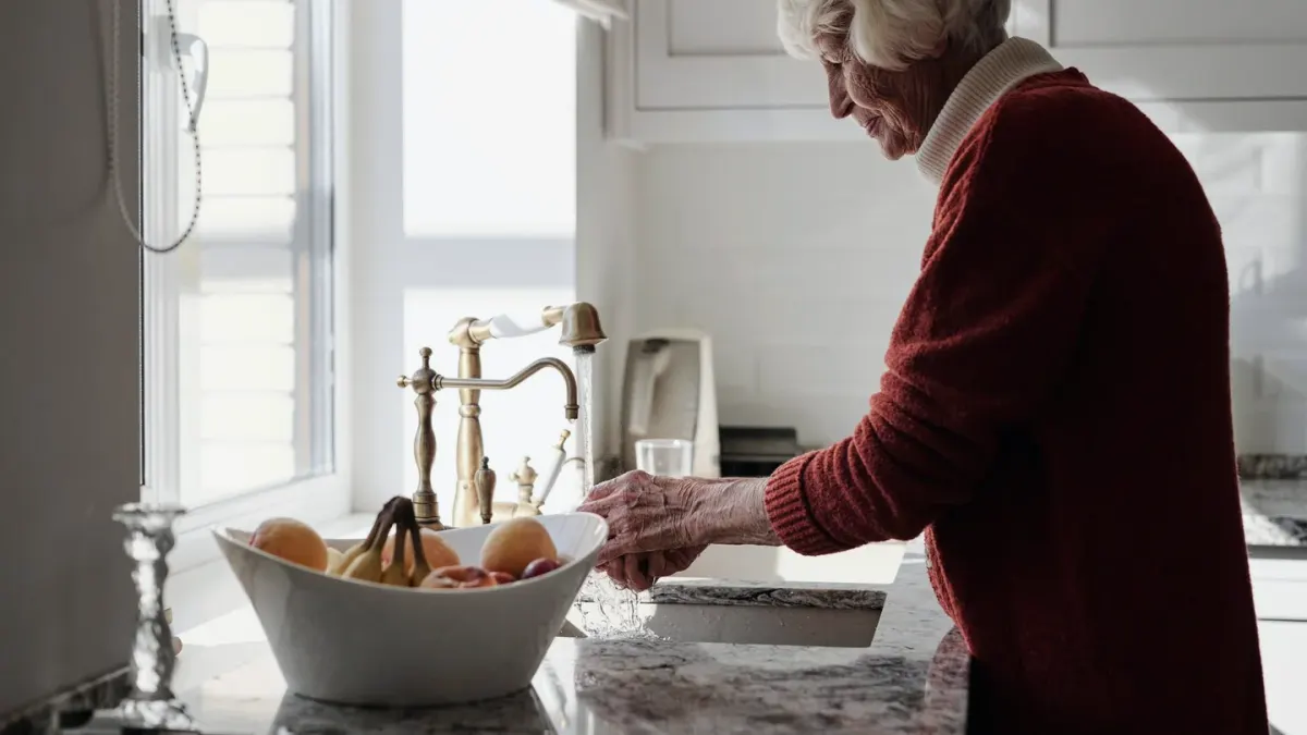 A gray-muzzled senior dog eating from a bowl in a home kitchen
