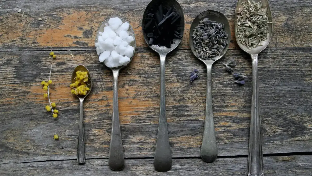 Dried valerian root pieces beside a small measuring spoon on a wooden surface