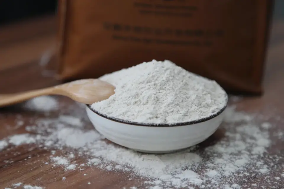 Slippery elm bark powder measured into a small bowl with a wooden spoon